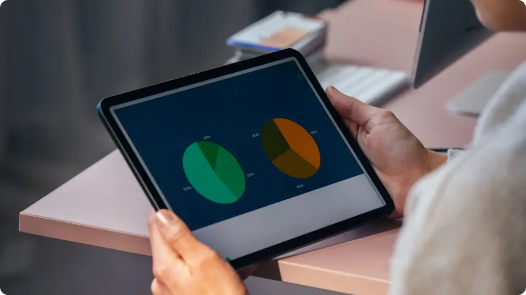 Persona revisando en una tableta dos gráficos circulares con datos de negocio